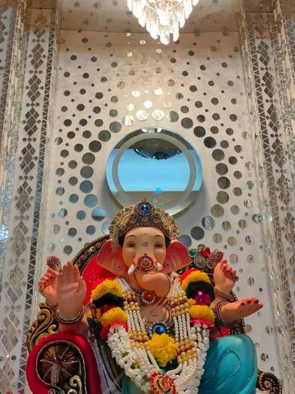 This setup shows how a Ganpati idol can be placed against an existing modern interior. The home's patterned mirror wall serves as a unique and reflective backdrop, enhancing the festive feel without needing a separate structure.