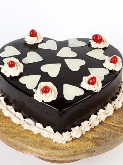 Show your love with this heart-themed chocolate cake. A rich, dark chocolate heart-shaped cake is decorated with small white chocolate hearts, creating a simple yet beautiful design for your special someone.
