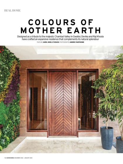 The main entrance to Terra features a custom-designed wooden door with a chevron pattern, flanked by a vibrant vertical garden. This entry sequence immediately establishes the home's connection to nature and craftsmanship.