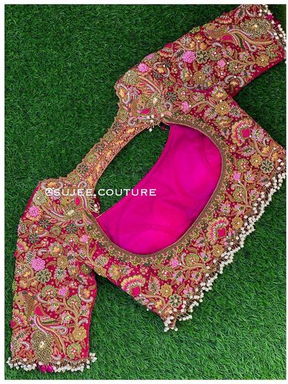 A full view of a luxurious pink velvet bridal blouse designed for a gold Kanchivaram saree. It features a large back cutout and is adorned with intricate zardozi, knot work, and pearl latkans.