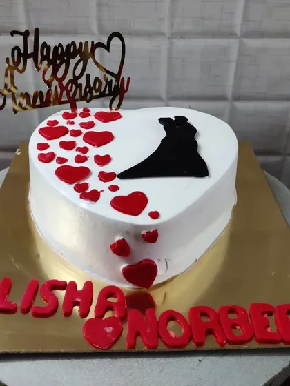 A romantic heart-shaped anniversary cake. This design features a silhouette of a couple and a cascade of red hearts.