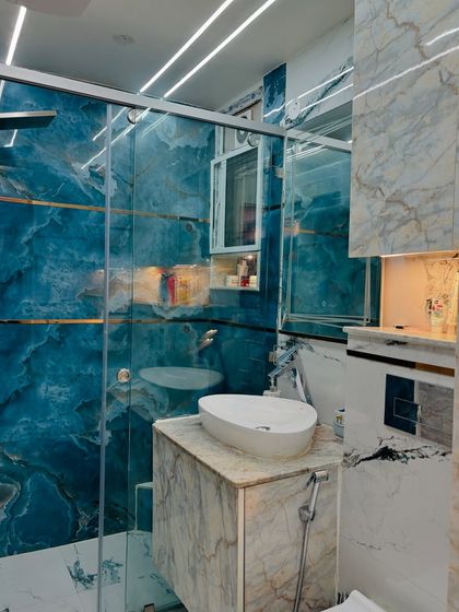 A stunning bathroom featuring bold blue marble tiles and a glass shower partition. The design creates a vibrant and luxurious atmosphere.
