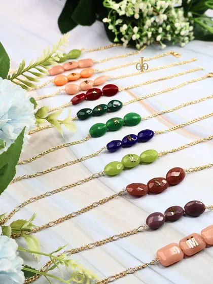 The full color range of our oval-shaped semi-precious stone Rakhis, each ready to be personalized with an initial.