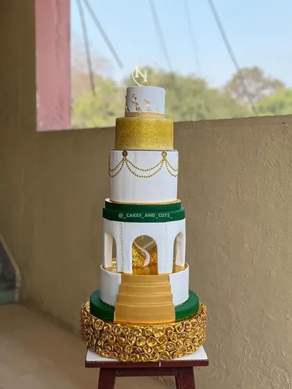 A clean, professional shot of our royal engagement cake, highlighting the different textures and colors of each tier, from the golden floral base to the monogrammed top.