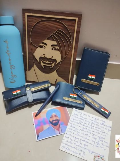A still shot of the blue leatherette combo, including the personalized water bottle and wooden portrait.