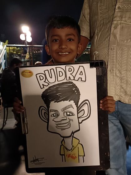 A young boy named Rudra with his caricature. It's a great souvenir from a family dinner.