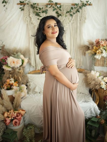 A classic and elegant portrait in a neutral-toned gown. The mother-to-be's pose is graceful and her expression is full of happy anticipation.