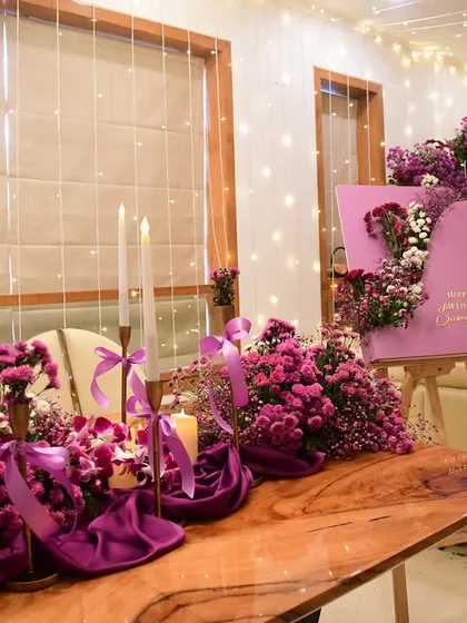 The custom welcome board for the party, featuring a unique curved design and a cascade of matching fresh flowers.
