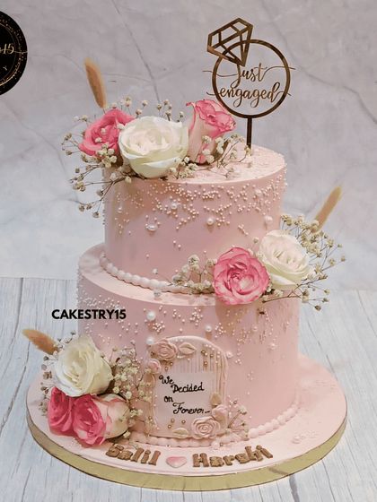 A lovely two-tier pineapple engagement cake in a soft pink hue. This 3kg cake is decorated with fresh white and pink roses, baby's breath, and a "Decided on Forever" plaque.