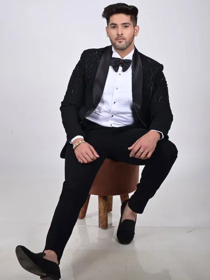 A studio shot of a model in our black tuxedo with subtle shoulder embellishments. It's a sophisticated and understatedly stylish look.