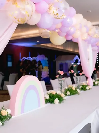 For the unicorn party, we designed a long guest table with a beautiful pastel balloon arch overhead and custom rainbow centerpieces. Every detail is planned to match the theme perfectly.