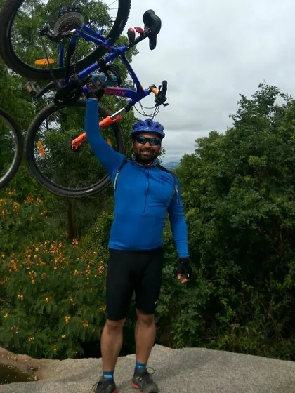 A rider triumphantly lifting his mountain bike after completing a challenging climb.