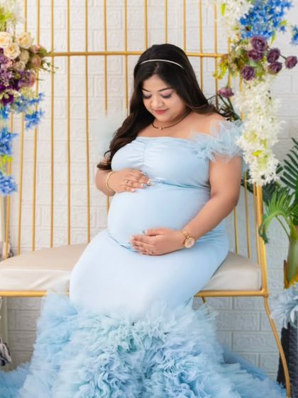 Another beautiful angle of the light blue mermaid gown. This pose shows the mother cradling her bump, with the ruffled train elegantly arranged around her.