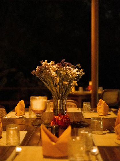 An intimate dinner setting with dried flowers and warm yellow napkins, creating a cozy and elegant atmosphere.
