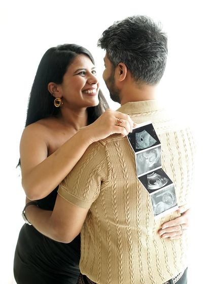 A playful and happy announcement, with the mother-to-be showing off the sonogram pictures on her partner's back.