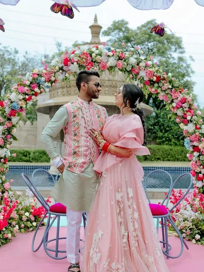 A sweet moment between the couple at their butterfly-themed Mehendi. The floral arch and whimsical decor create a perfect fairytale setting.