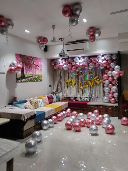 For a simple yet impactful at-home surprise, I can fill a room with balloons. This setup uses chrome pink and silver balloons on the floor and ceiling, with a 'MY LOVE' foil balloon message as the focal point.