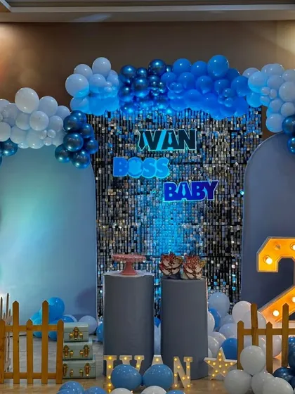 Here is a modern and stylish Boss Baby theme for a second birthday. I used a blue shimmer wall as the central backdrop, framed by a balloon arch in shades of blue and white, with custom neon lettering and a light-up number '2' to complete the look.
