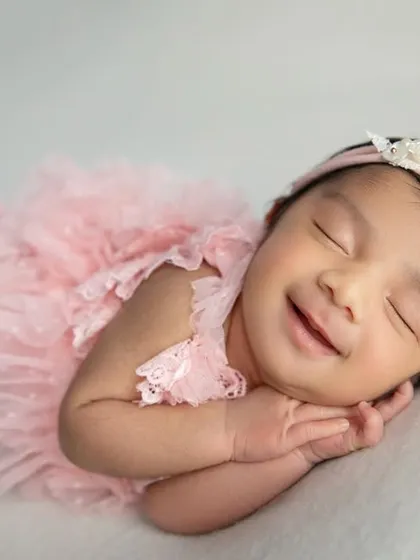The best moment to capture. A big, happy, sleepy smile from a baby girl in her pink outfit. These are the moments that make parents' hearts melt.