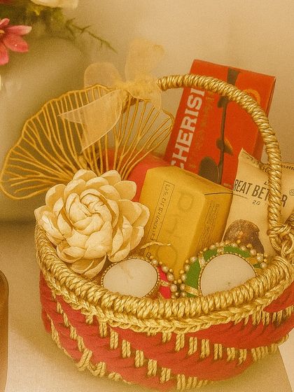 Our Diwali Bliss hamper is presented in a vibrant red handcrafted Jali basket. It's a traditional delight, containing Phool incense cones, decorative tealights, chocolate almonds, and chocolate laddoos.