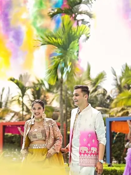 A grand entrance for the couple at the poolside Haldi, complete with colorful smoke effects creating a rainbow in the sky.