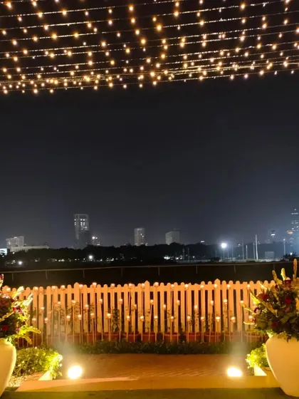 A beautiful view of the Mumbai skyline from the reception venue. The decor is designed to complement the view, with a canopy of fairy lights and large floral arrangements framing the scene.