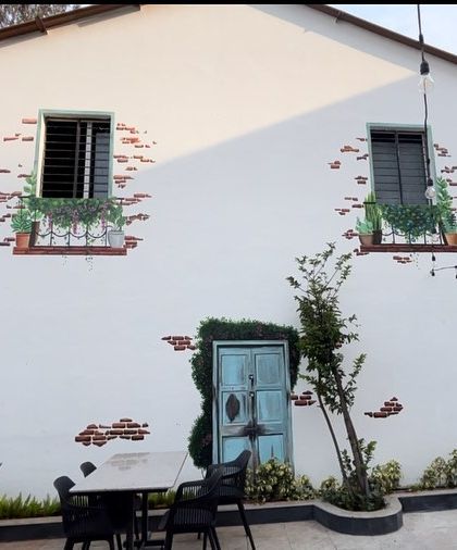 The full view of the cafe's exterior wall, where the painted door and windows create a pleasant, European-style illusion.