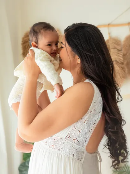 A mother holds her baby close, sharing a sweet kiss. This image from a 6-month session is a perfect example of the tender, loving moments I aim to capture.