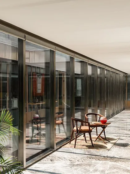 The top floor corridor is defined by a striking greyish-white marble floor and a fluted glass and wood paneled wall, setting a distinct, elevated aesthetic for the executive level.