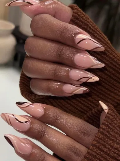 A sophisticated abstract design with swirls of brown and nude tones on long stiletto nails. This look is modern, chic, and incredibly stylish.