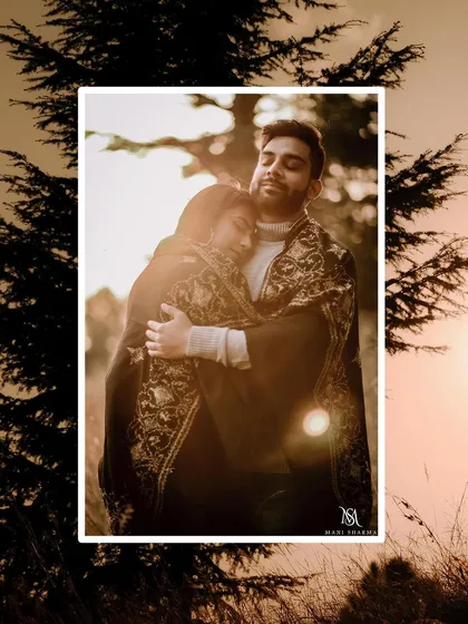 A cozy and romantic portrait taken at sunset. The couple is wrapped in a warm shawl, creating a feeling of intimacy against the beautiful backdrop of the setting sun.