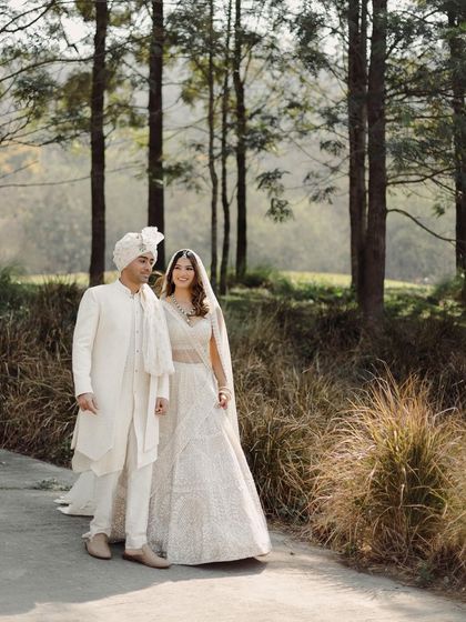 A full-length portrait that captures the couple's elegance and the beauty of their natural surroundings. Their comfortable stance and gentle smiles make this a perfect, timeless wedding photograph.