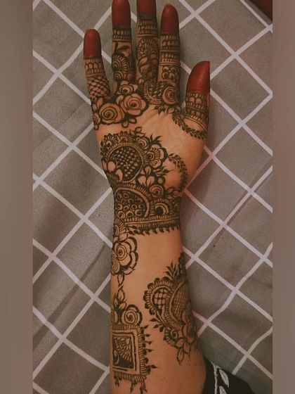 The stained result of an intricate bridal design. The deep red color highlights the detailed rose patterns and paisley motifs, covering the hand and arm beautifully.