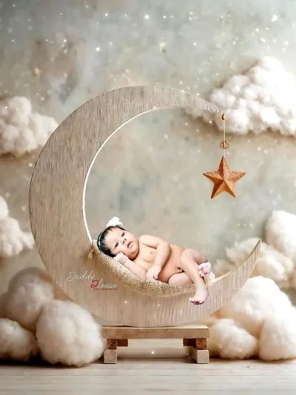 A peaceful newborn portrait featuring a baby sleeping on a wooden crescent moon prop, surrounded by soft, dreamy clouds. These sessions are designed to be calm and safe for your little one.