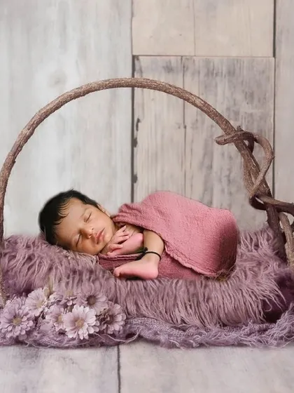 A simple and serene newborn pose in a rustic basket. The soft lighting and earthy tones create a calm and natural feel.