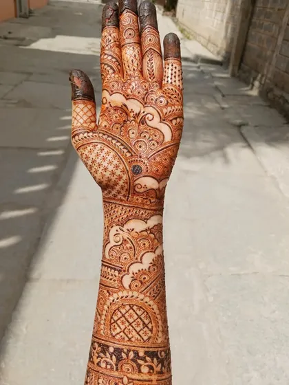 This is a full bridal mehendi I practiced on myself, inspired by one of my favorite artists. It features cloud-like swirls, intricate netting, and varied finger designs, covering the hand and arm completely.