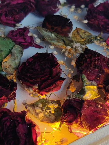 This resin block preserves a client's bouquet of roses, turning them into a permanent piece of art. The wooden base with an LED light makes the flowers glow beautifully.