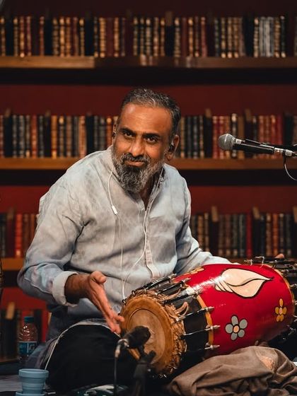 A close-up of Pramath Kiran, smiling as he plays the mridangam. His deep knowledge of traditional Indian percussion is the anchor of our rhythm section.