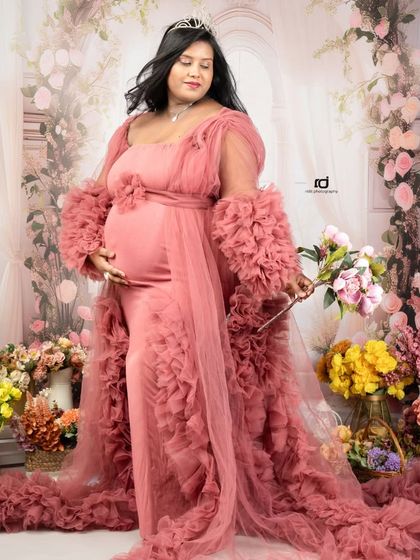 A fairytale moment for the mom-to-be. Dressed in a dusty rose gown with a tiara, standing against a floral arch, this portrait is pure magic.