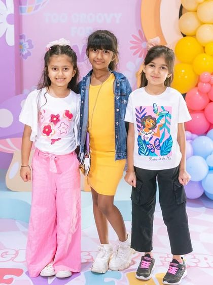 The birthday girl and her friends posing in front of the colorful, groovy backdrop. I create settings that kids love and where they can have fun with their friends.
