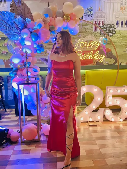 A side view showing the movement of the red satin gown. The thigh-high slit adds a touch of drama to the classic silhouette.