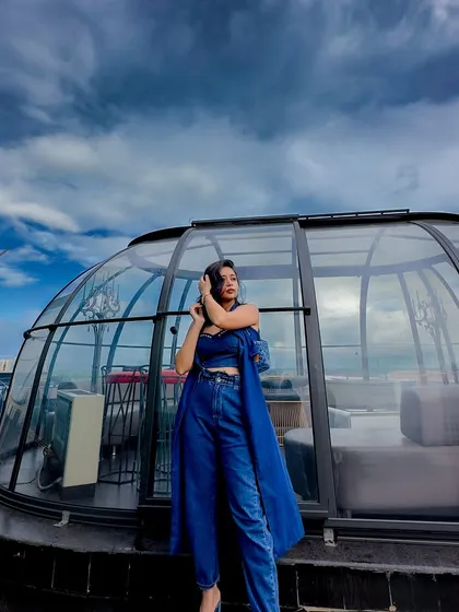 Posing in front of a glass igloo on the rooftop. The modern architecture complements the chic, urban look.