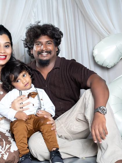 A family celebrating their son's second birthday with a number '2' balloon and coordinated outfits.