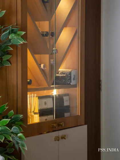 Storage can be beautiful. This close-up shows a thoughtfully styled bar cabinet, where the geometric wooden doors and warm interior lighting turn a functional piece into an elegant display.