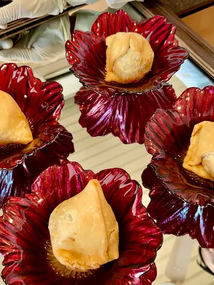 Hot, fresh samosas presented in beautiful red glass flower bowls, elevating a simple snack to a work of art.