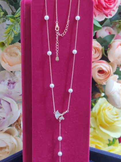 A delicate pearl and silver necklace with a charming bow pendant, perfect for a graceful and feminine style.