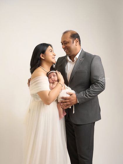A shared look of wonder between new parents as they hold their baby. This portrait captures the beginning of their journey as a family of three, filled with love and admiration for their little one.