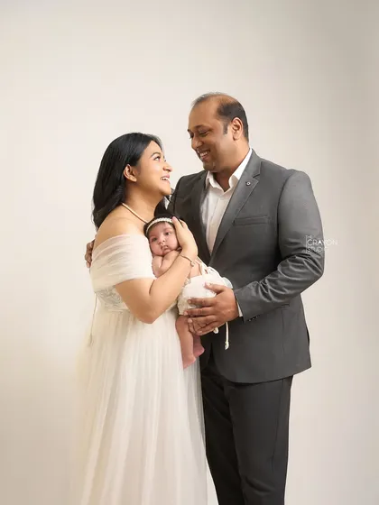 A candid moment where the new parents share a look of love and joy while holding their baby. It’s a beautiful portrait of a new family of three.