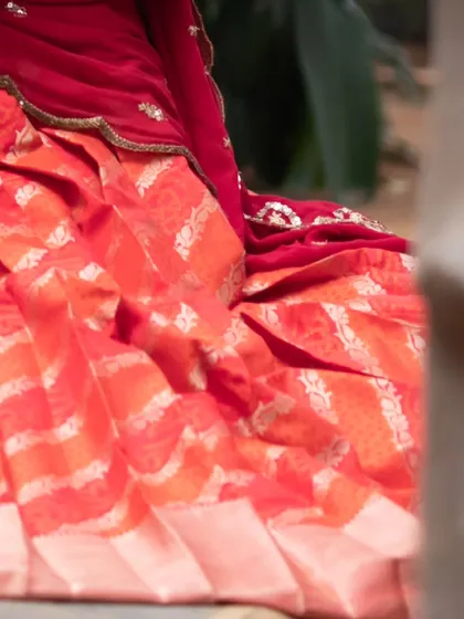 A glimpse of a red brocade lehenga, showcasing the rich texture and traditional weaving.