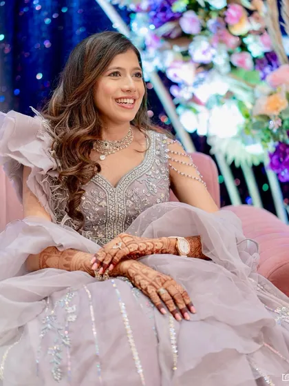 A happy, seated shot of this bride at her engagement. Her lavender gown with ruffled details is so unique, and the soft makeup lets the outfit shine.